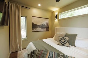 A bedroom with a bed, a painting, a window, and a curtain. - The Collins - Luxury Treehouse (Pikeville)