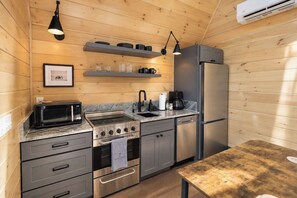 Eine kleine Küche mit Mikrowelle, Herd, Spüle und Kühlschrank.