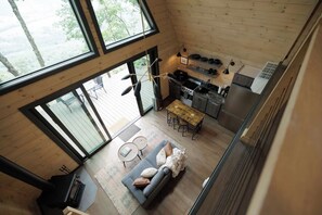 A high-ceilinged room with a dining area, kitchen, and large windows. - The Sutter - Luxury Treehouse (Pikeville)