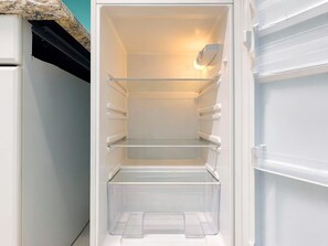 An interior of a white refrigerator with multiple shelves and a freezer compartment. - Comforting Beach Front Condo with pool and hot tub (Daytona Beach)