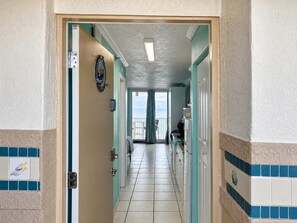 Step through the entryway and glimpse the open layout ahead—tile floors lead you straight to glass doors and a balcony framing the coastline. Calming teal accents set the mood for your coastal escape. - Comforting Beach Front Condo with pool and hot tub (Daytona Beach)