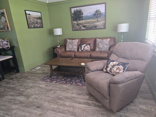 A living room with a brown sofa, a matching armchair, a coffee table, and two lamps.
