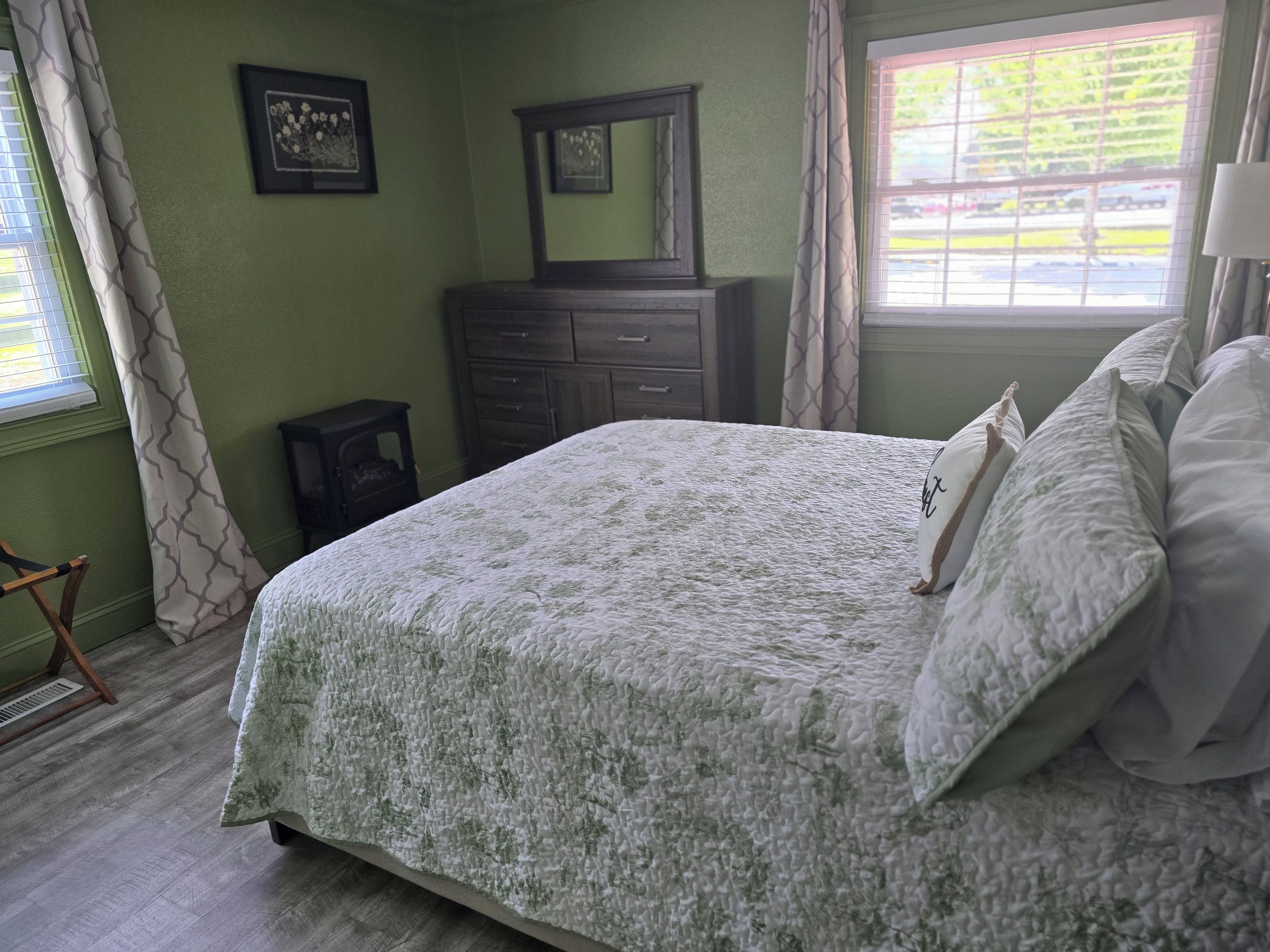 Une chambre à coucher avec un lit, une commode et une fenêtre avec des rideaux.