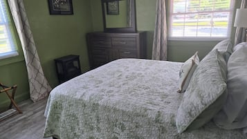 Une chambre à coucher avec un lit, une commode et une fenêtre avec des rideaux.