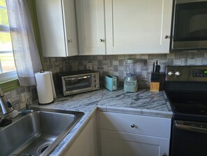 A kitchen with a sink, a toaster, a blender, and a microwave.