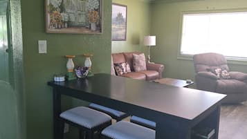 Un área de comedor con una mesa y sillas, un sofá, una lámpara y un ventilador de techo.