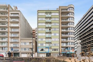 A multi-story residential building with balconies, a parking area, and a street view. - Parkside Stay Near Beach (Blankenberge)