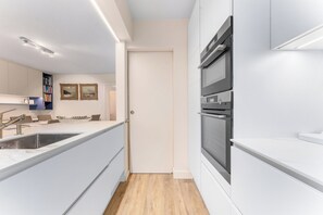 A modern kitchen with a built-in oven, a sink, and a countertop. - Parkside Stay Near Beach (Blankenberge)
