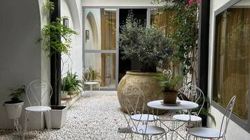 Une cour avec un espace aménagé pour s’asseoir, des plantes et un grand bac à fleurs.