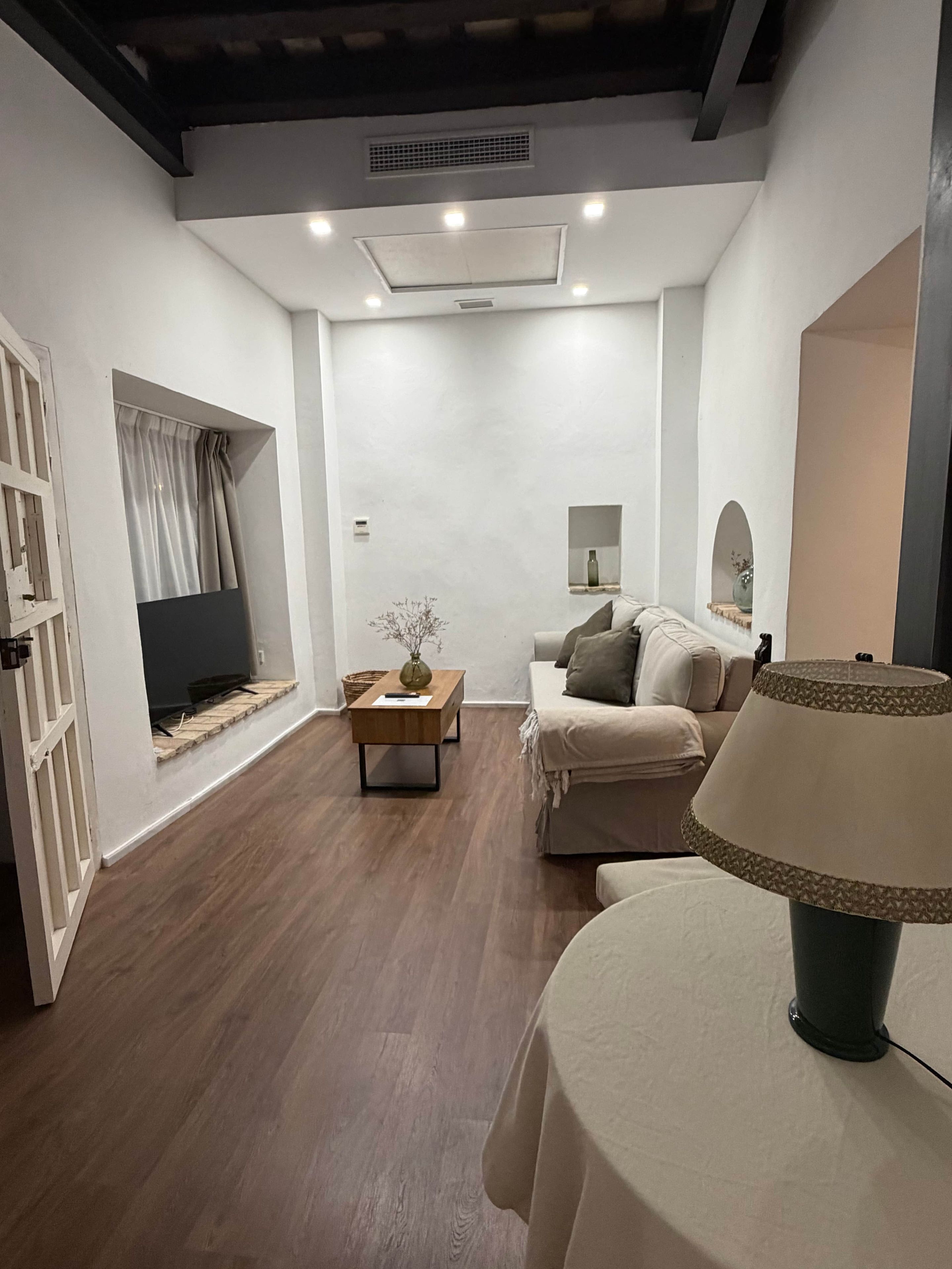 Un salon moderne avec un canapé, une table basse, une lampe et un téléviseur.