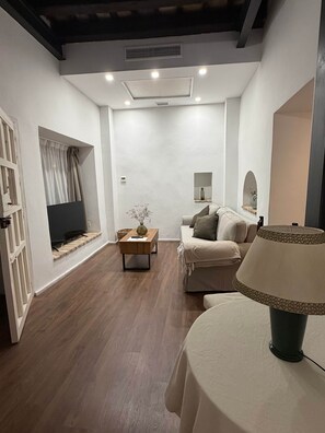 Un salon moderne avec un canapé, une table basse, une lampe et un téléviseur.