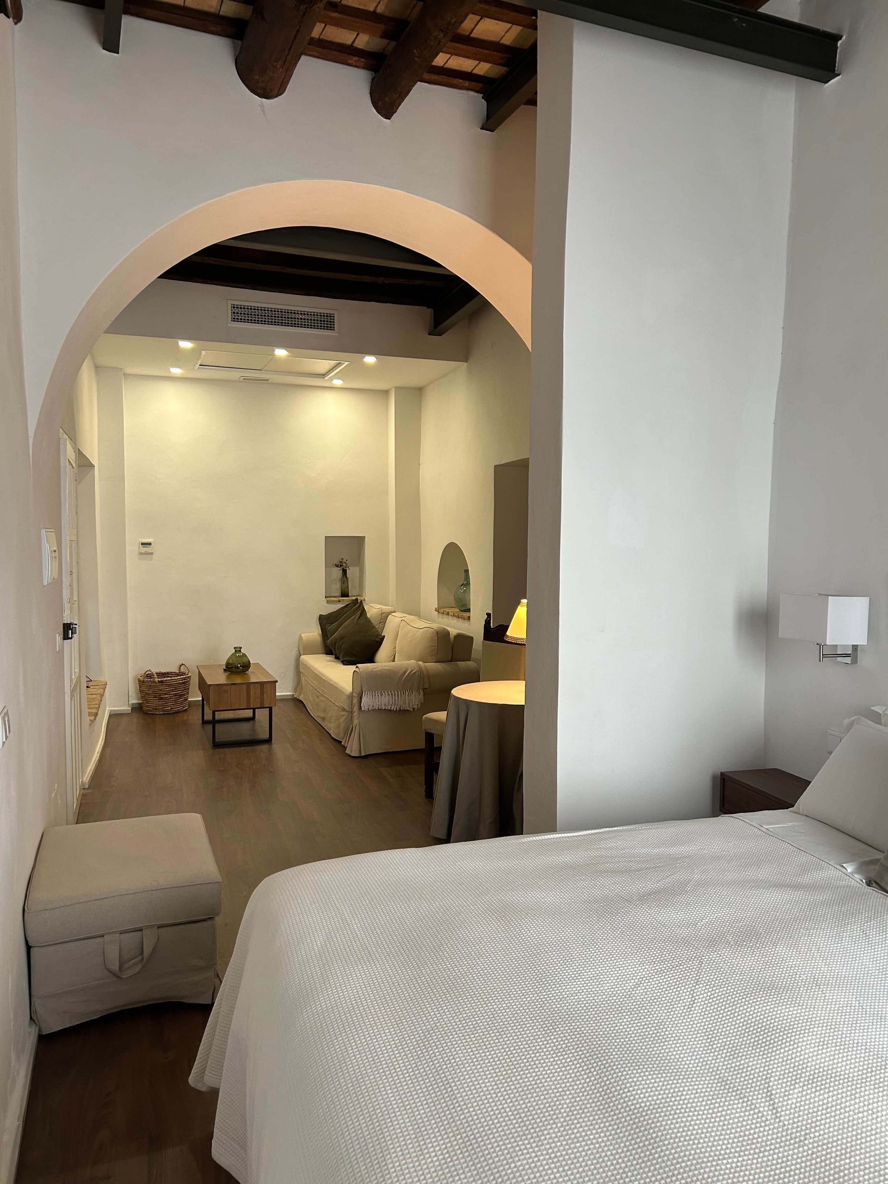 Une chambre d’hôtel comprenant un lit, un coin salon avec une table et des chaises, ainsi qu’un espace de vie séparé avec un canapé et une lampe.