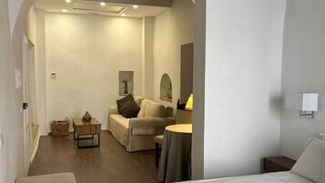 Une chambre d’hôtel comprenant un lit, un coin salon avec une table et des chaises, ainsi qu’un espace de vie séparé avec un canapé et une lampe.