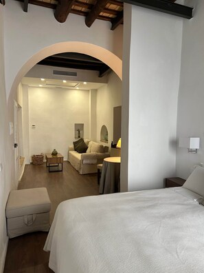 Une chambre d’hôtel comprenant un lit, un coin salon avec une table et des chaises, ainsi qu’un espace de vie séparé avec un canapé et une lampe.