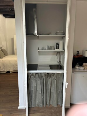 Une petite cuisine équipée d’un évier, d’un four à micro-ondes et d’un petit réfrigérateur.