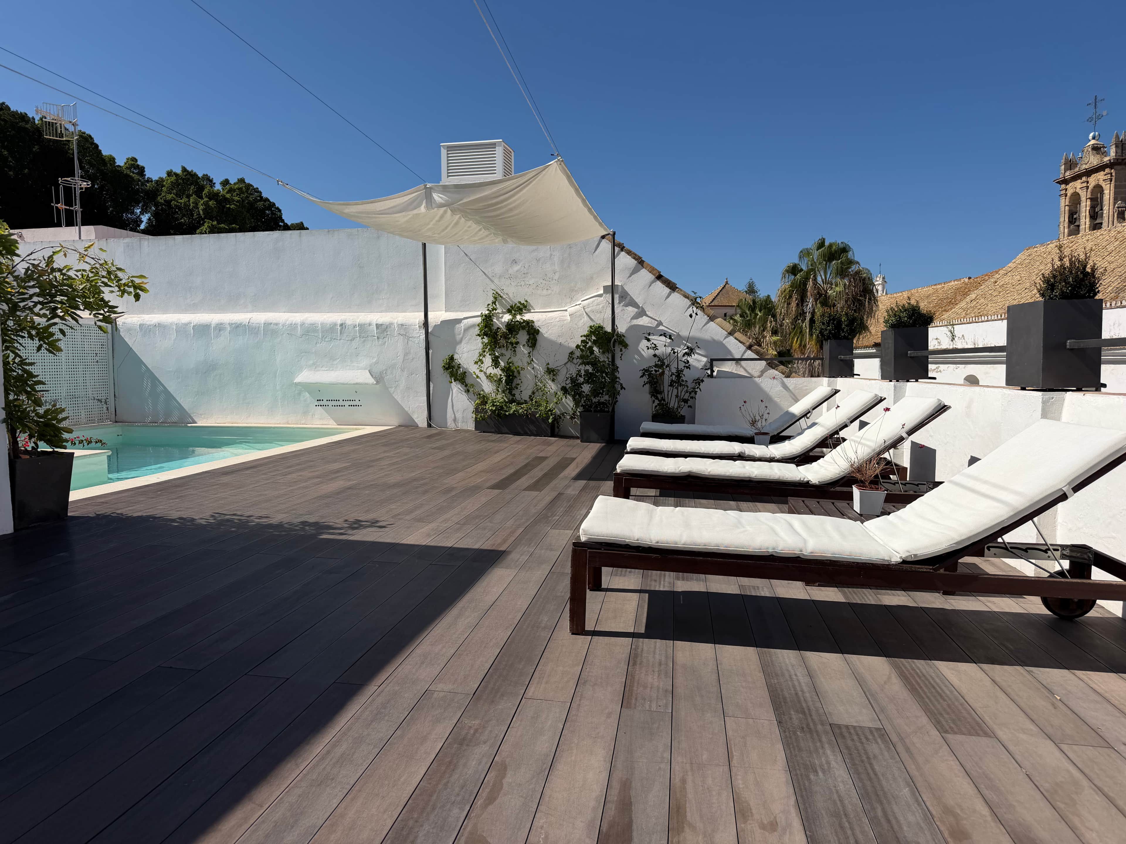 A rooftop pool area with lounge chairs and a water feature.
