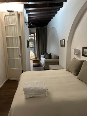 Une chambre à coucher comprenant un lit, un canapé, une petite table et une porte donnant sur un balcon.