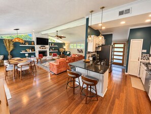 A spacious living area with a fireplace, a dining set, and a kitchen with modern appliances. - Palm & Pine  (Ocean Springs)