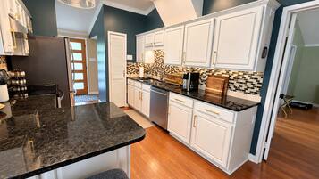 Una cocina moderna con armarios blancos, encimera de granito negro y salpicadero con un diseño de mosaico.