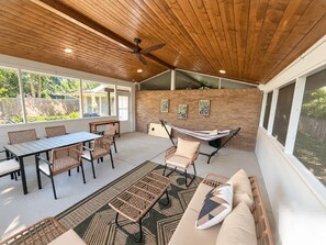 Un patio techado con mesa, sillas, una hamaca y un sofá.