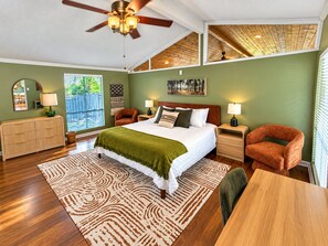 A bedroom with a bed, two nightstands, a dresser, a chair, a table, a ceiling fan, and a window. - Palm & Pine  (Ocean Springs)
