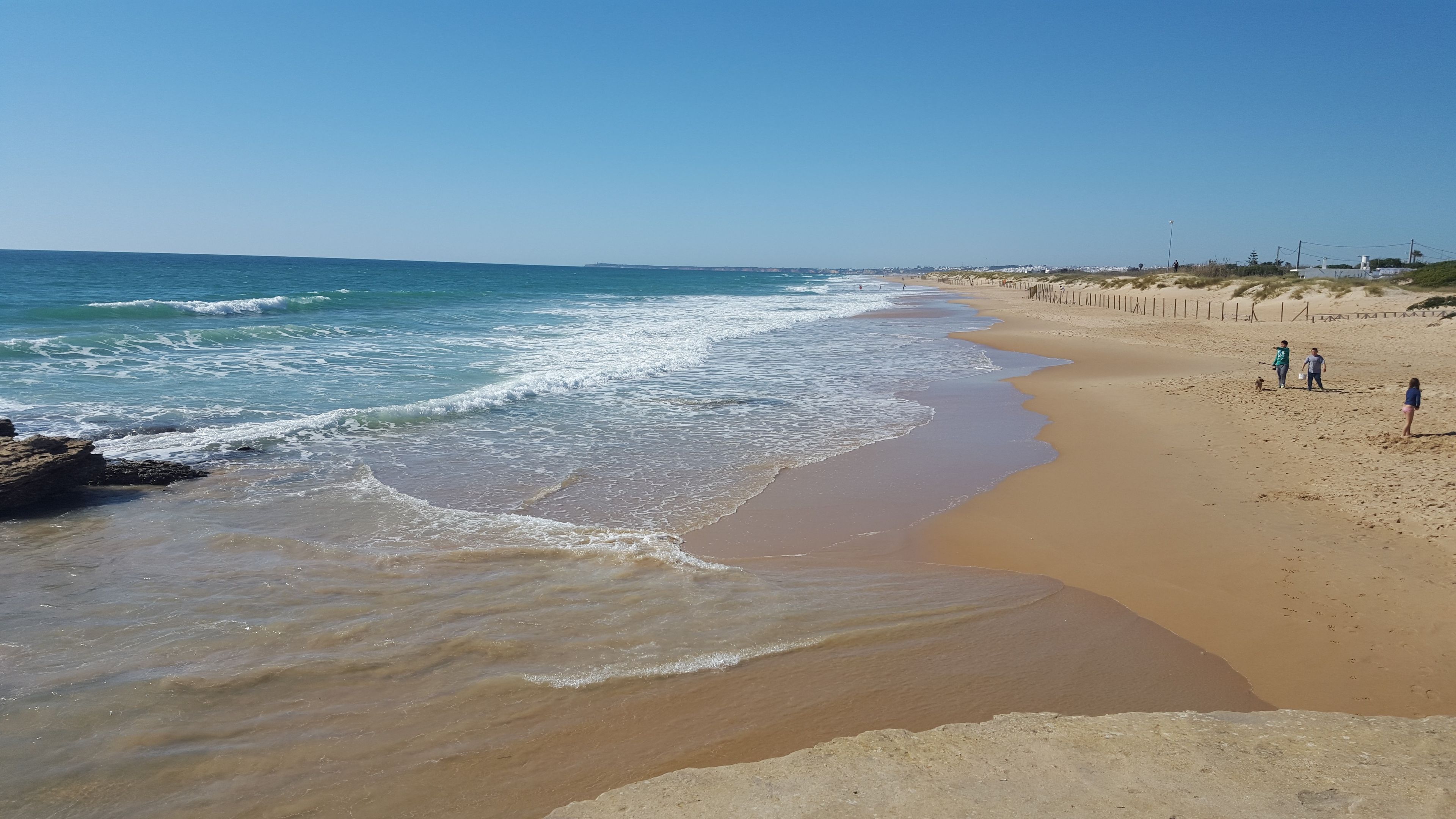 Una playa con arena dorada y olas suaves.