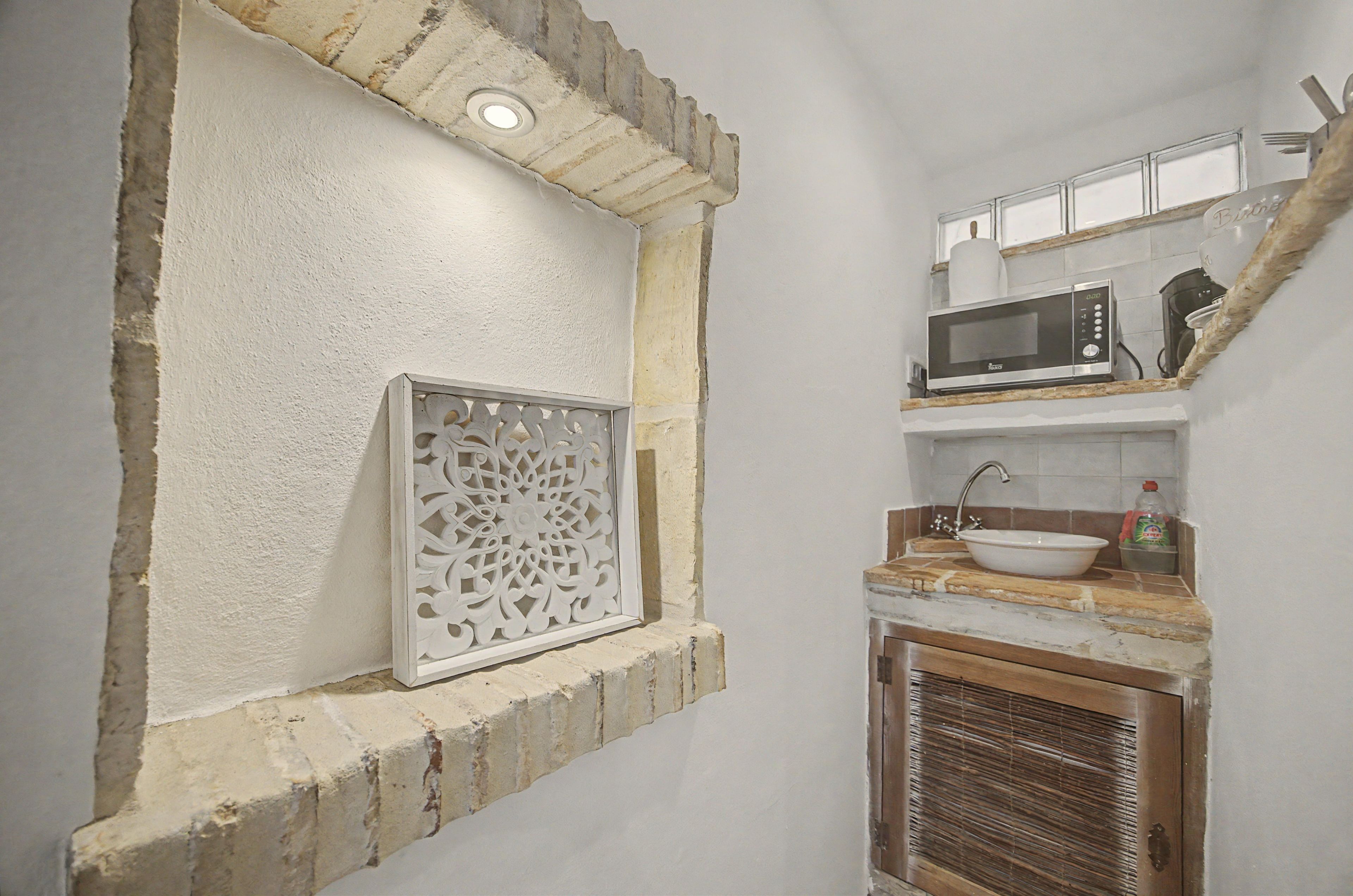 A kitchen with a microwave, sink, and decorative wall panel.