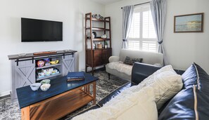 Een woonkamer met een televisie, een houten boekenkast, een bank en een salontafel.