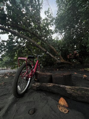 A bicycle parked on a rocky surface with trees in the background. - Villa Keköl - Casa Numa (Puerto Viejo de Talamanca)