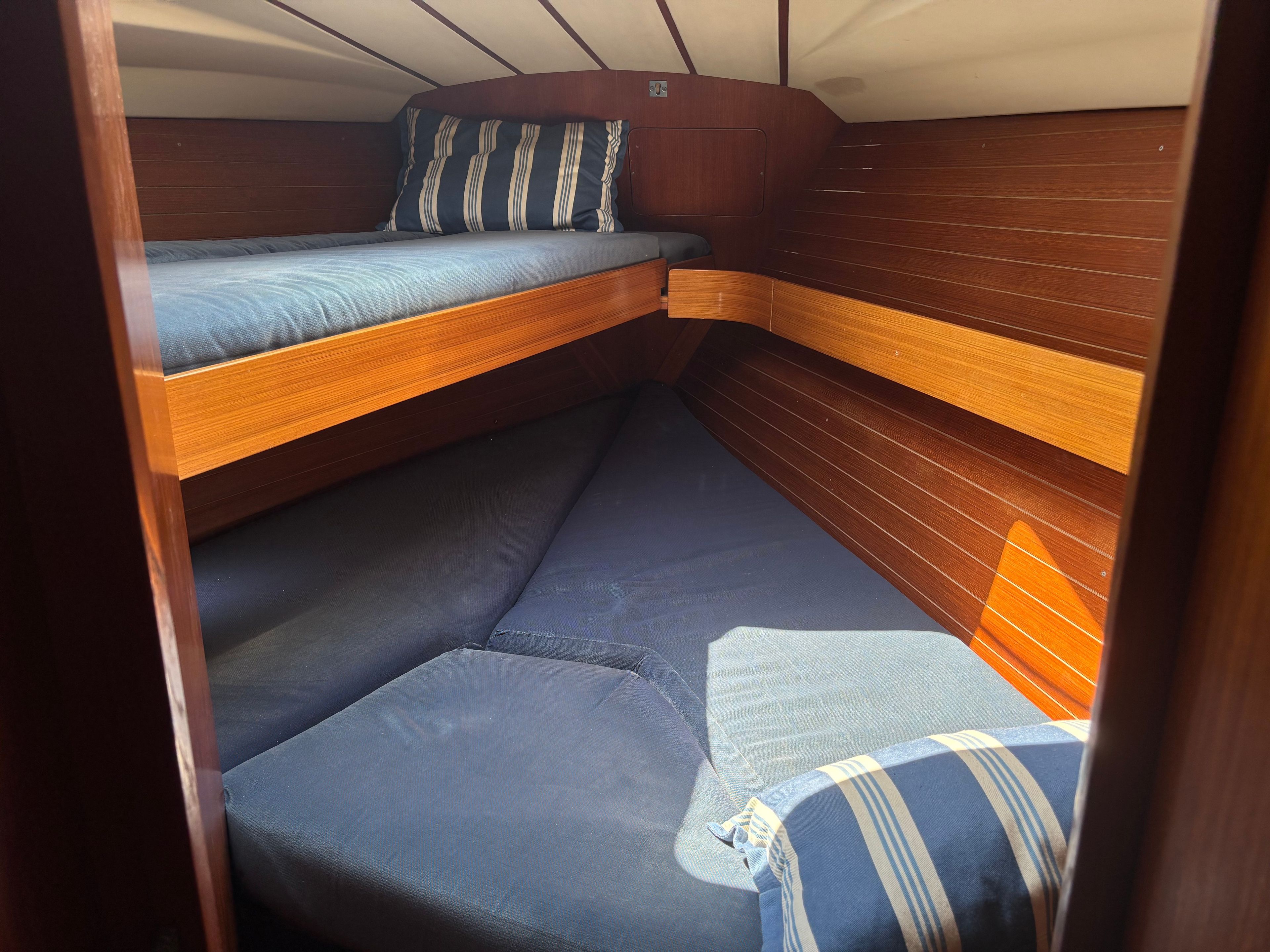 A compact, wooden interior with a bunk bed and a lower seating area.