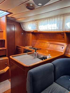 A compact galley with a sink, stove, and storage cabinets.