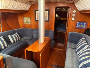 A compact interior with a sofa, a small table, and a bench. - Spend the Night on a Sailboat in Lagos (Lagos)