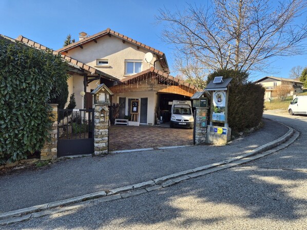 A two-story house with a garage, a gravel driveway, and a solar panel on the roof.