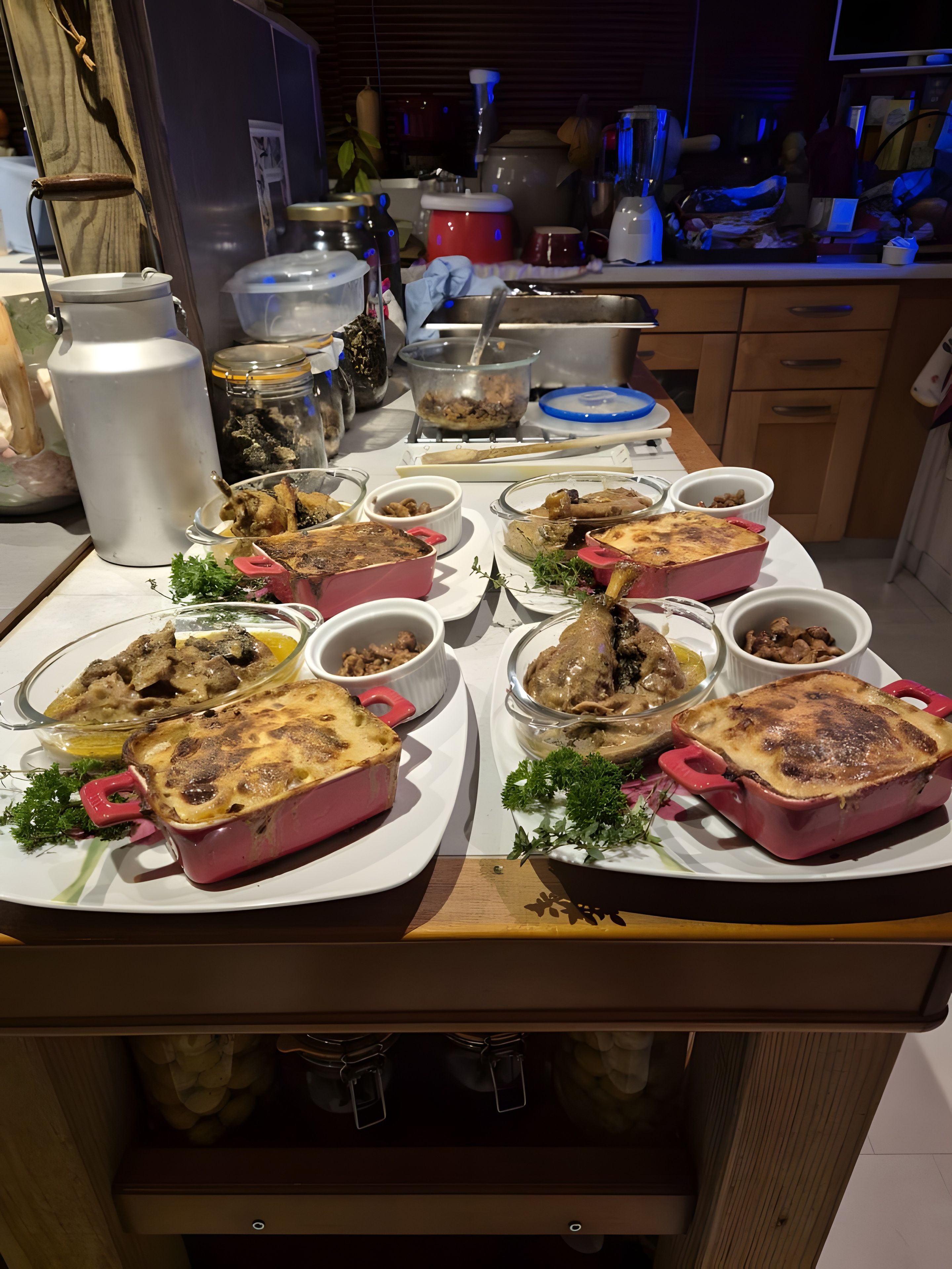 Un plan de travail de cuisine sur lequel se trouvent de nombreux plats, notamment des plats à four et des saladiers, ainsi qu’une variété d’appareils et d’ustensiles de cuisine.