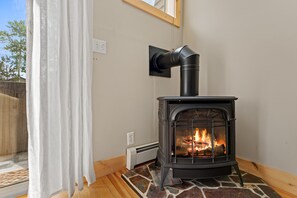 A wood-burning stove with a chimney, a stone hearth, and a power outlet on the wall. - New 2-bedroom townhome with private hot tub (Silverthorne)