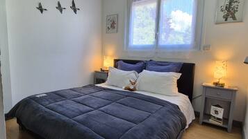 Een slaapkamer met een groot bed, twee nachtkastjes, een raam met gordijnen en vogeldecoraties aan de muur.