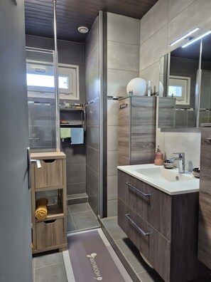 Un baño moderno con cabina de ducha de vidrio, tocador con espejo y barra para toallas.