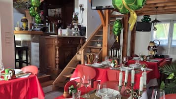 Een restaurant met rode tafelkleden, witte kaarsen en een houten trap.