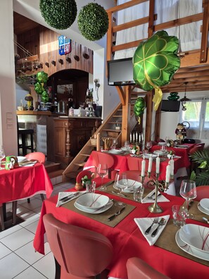Un restaurante con manteles rojos, velas blancas y una escalera de madera.