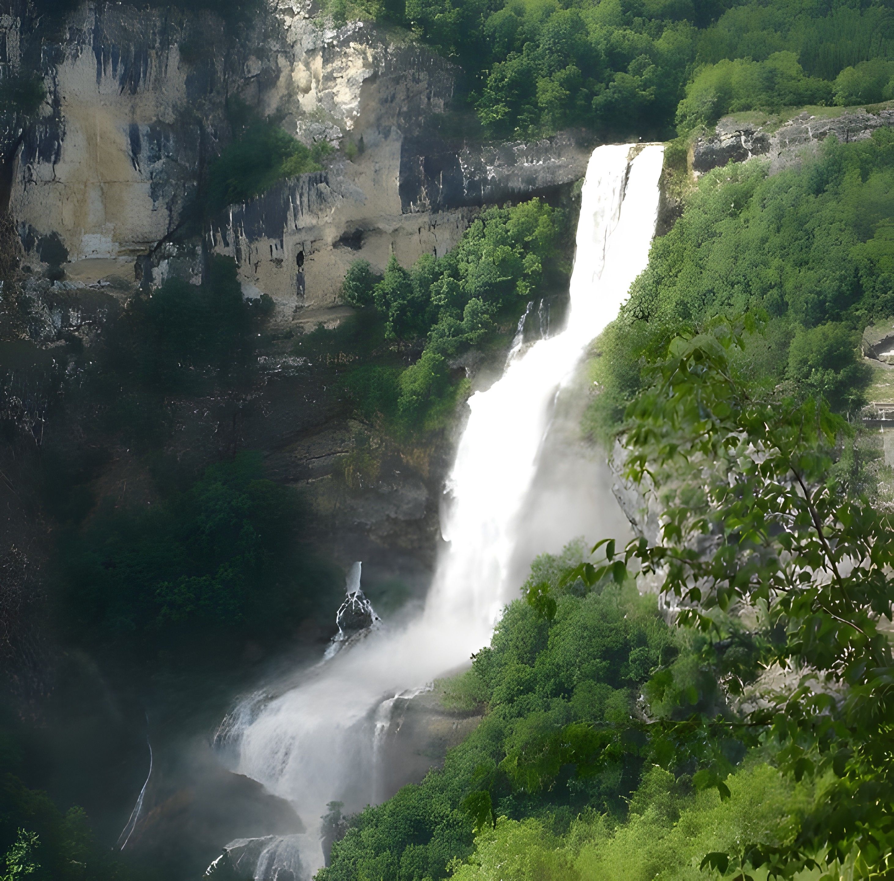 A waterfall cascading down a rocky cliff surrounded by lush greenery.