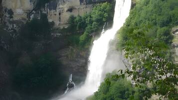 A waterfall cascading down a rocky cliff surrounded by lush greenery.