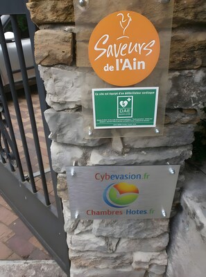 Señal que indica un centro médico y un hotel, con la leyenda 'Sauveteurs de l'Ain' y 'Cybevasion.fr Chambres Hôtes.fr'.