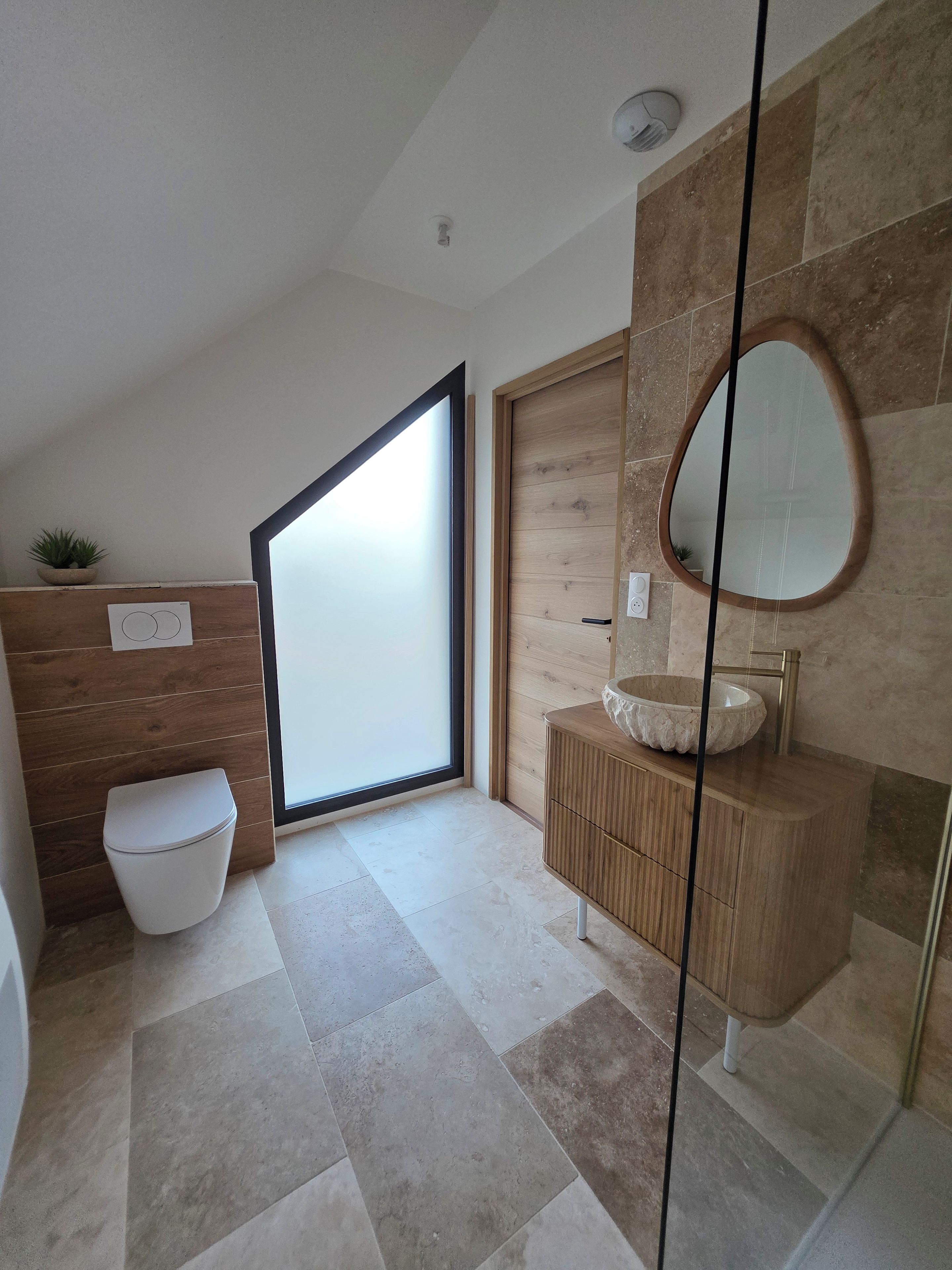 A modern bathroom with a toilet, sink, and large mirror.
