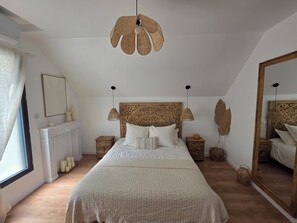 Un dormitori amb un llit gran, un ventilador de sostre, un mirall i una llar de foc.
