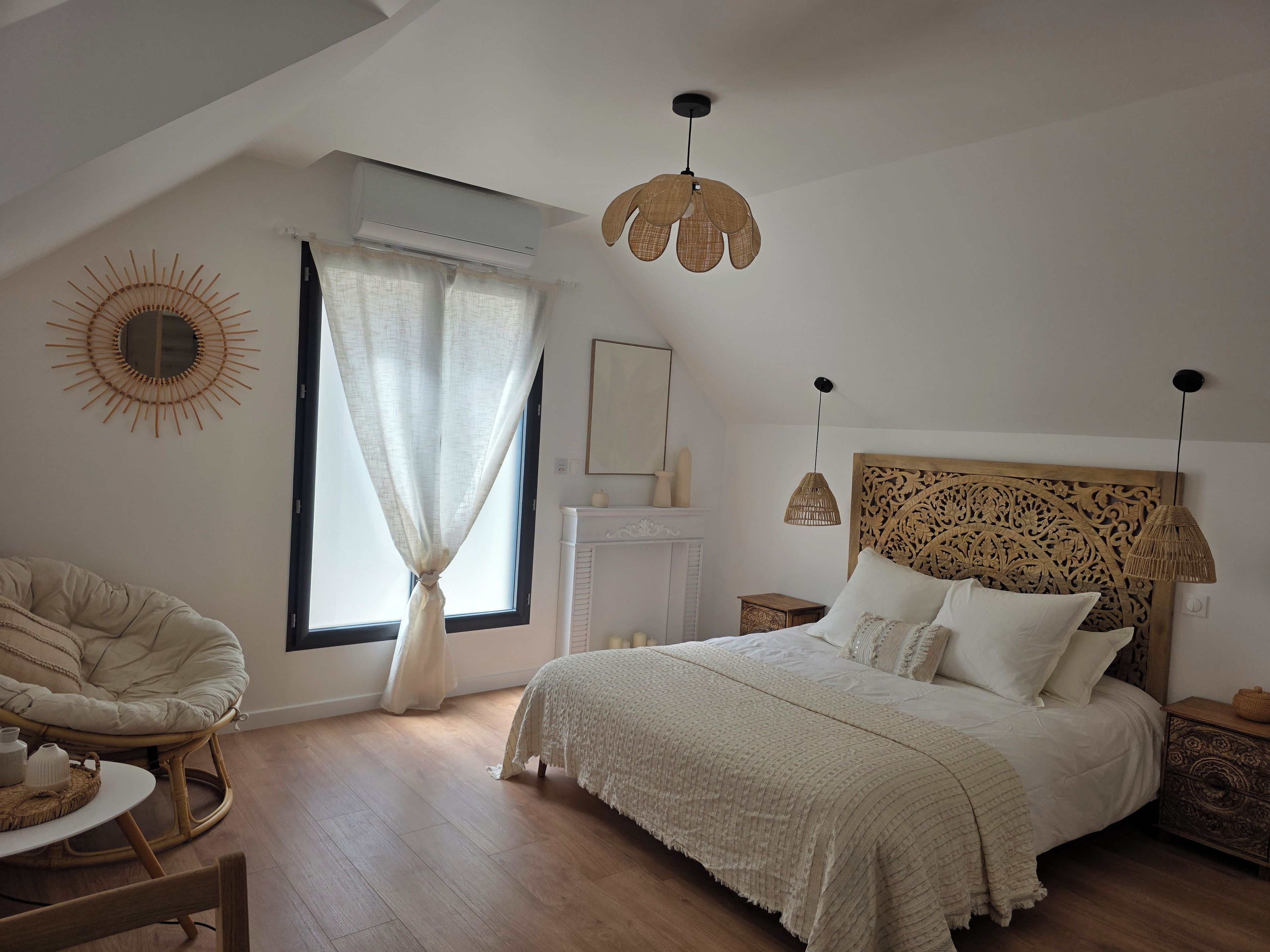 A bedroom with a bed, a chair, a fireplace, and a window with curtains.