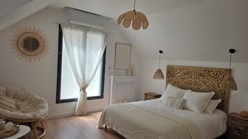 A bedroom with a bed, a chair, a fireplace, and a window with curtains.