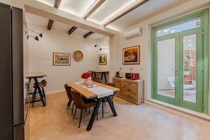 Uma área de refeições com uma mesa de madeira, cadeiras e um pequeno armário.