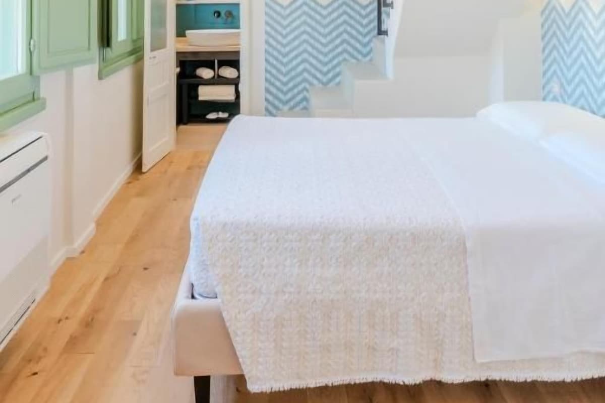 Quarto com cama, guarda-roupa e escada.