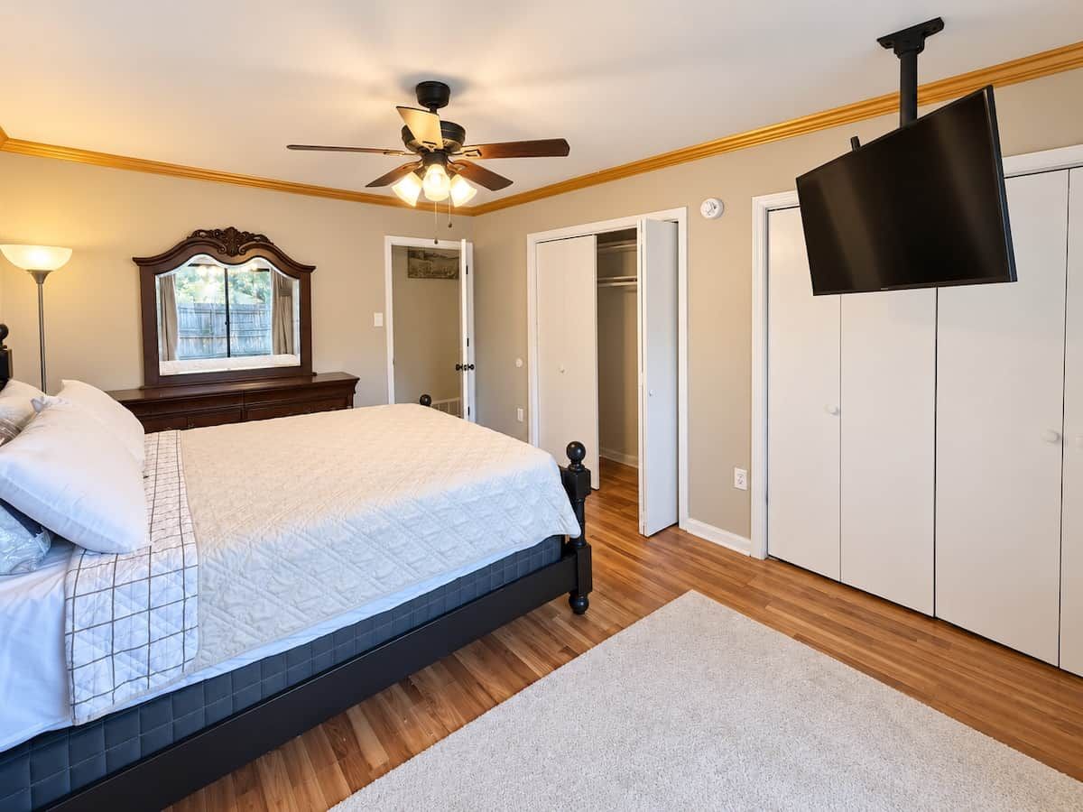 Ein Schlafzimmer mit Bett, Deckenventilator, Fernseher und Kleiderschrank.