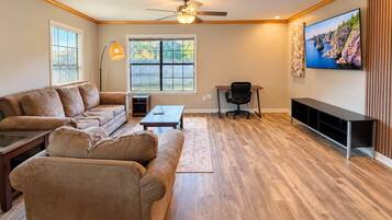 A living room with a sofa set, a coffee table, a TV mounted on the wall, and a fireplace.